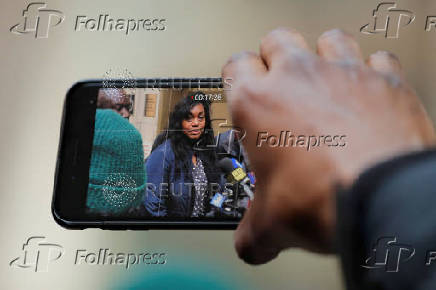 FILE PHOTO: A man uses his phone to take video of Tamara Lanier speak to the media, outside of the Harvard Club in New York