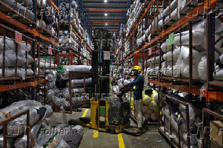 A worker moves rolls of fabric in a forklift in a garment manufacturing unit on the outskirts of Ahmedabad
