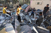 Palestinians inspect the damage at the site of an Israeli strike on a house, in Deir Al-Balah in the central Gaza Strip