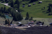 A few remaining houses are seen after a massive rock and ice slide covered most of the village of Blatten