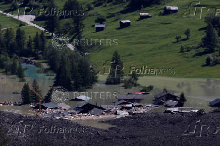 A few remaining houses are seen after a massive rock and ice slide covered most of the village of Blatten