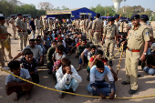 FILE PHOTO: Police officers stand next to men they believe to be undocumented Bangladeshi nationals after they were detained during raids in Ahmedabad