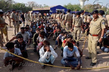 FILE PHOTO: Police officers stand next to men they believe to be undocumented Bangladeshi nationals after they were detained during raids in Ahmedabad