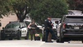 Police stand at a crime scene as they searched for a suspect posing as a police officer who shot two Democratic state lawmakers