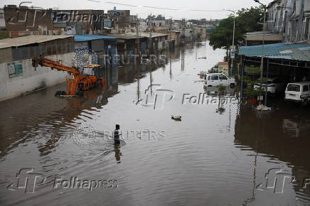 A man wades through water, as streets are flooded after torrential rain, in Ahmedabad