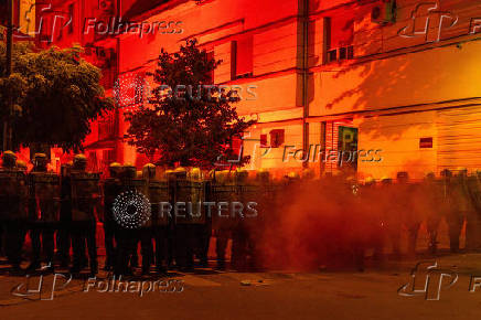 Police officers stand guard during a standoff between ruling party supporters and anti-government protesters in Novi Sad