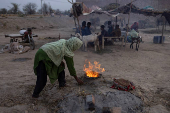 Woman ignites mud tandoor oven for chapatis in Multan