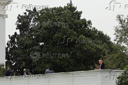 U.S. President Trump talks with architect McCrery as they walk on the roof of the White House in Washington