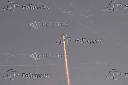 A military aircraft flies in the sky following a barrage of missiles launched from Iran, as seen over Tubas