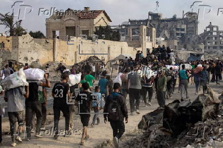 Displaced Palestinians carry relief parcels along Rashid Street, west of Gaza City