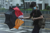 A man struggles with an umbrella while walking against strong wind, as Typhoon Wipha approaches, in Hong Kong