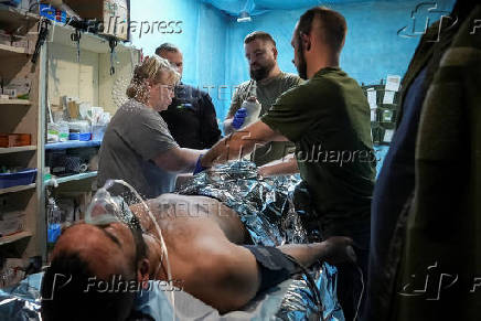 Medics help a wounded Ukrainian serviceman at a medical stabilisation point, near the town of Pokrovsk, in Donetsk region