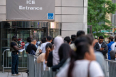 An ICE agent speaks to people lined up to enter the U.S. Immigration Court, in Manhattan