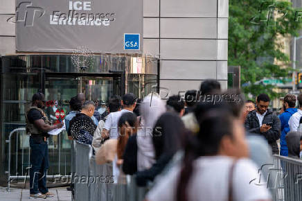 An ICE agent speaks to people lined up to enter the U.S. Immigration Court, in Manhattan