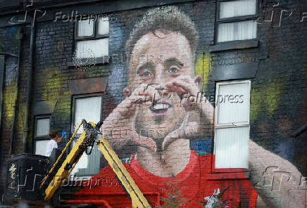 Artist John Culshaw works on a mural of late Liverpool player Diogo Jota on the side of a pub in Liverpool