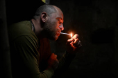 A Ukrainian serviceman lights up a cigarette at a position in a front line in Zaporizhzhia region