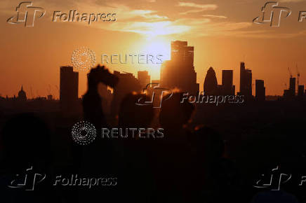 People watch the sunset over City of London