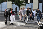 People, including members of the clergy, walk across a road as they arrive at the Vatican after the election of Pope Leo XIV, as seen from Rome