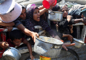 Palestinians wait to receive food from a charity kitchen, in Gaza City