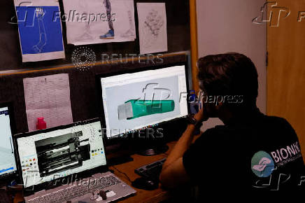 Technician works on computers with prosthetic limb diagram at the Bioniks Private Limited, in Karachi