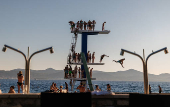 People jump into the Adriatic sea during warm weather in Zadar