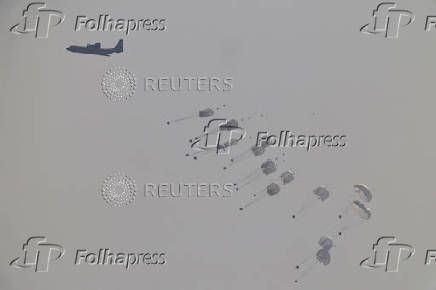 Aid packages dropped from an airplane descend over Gaza Strip, as seen from Israel