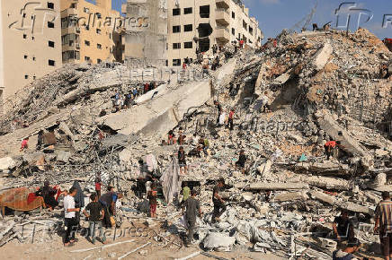 Palestinians inspect the site of an Israeli air strike that destroyed a residential building, in Gaza City