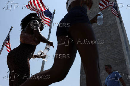 People carry bottles of cold water during a heatwave affecting the eastern U.S., in Washington