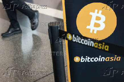 A man walks past a signage that displays the logo of the Bitcoin Asia conference