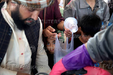 An Afghan boy, who recently was deported from Iran, waits in line to receive sweet drink at a camp for returning migrants near the Islam Qala border crossing