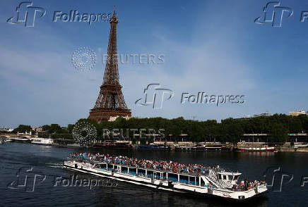 A tourist boat travels on the River Seine and the Eiffel Tower in Paris