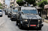 Israeli military vehicles drive through a street during an Israeli raid in Nablus