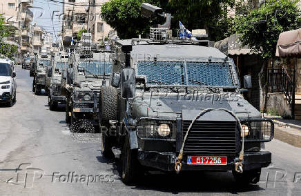 Israeli military vehicles drive through a street during an Israeli raid in Nablus