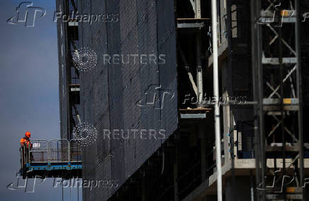 FILE PHOTO: A construction worker stands on a platform on a new apartment building under construction in Manchester, Britain