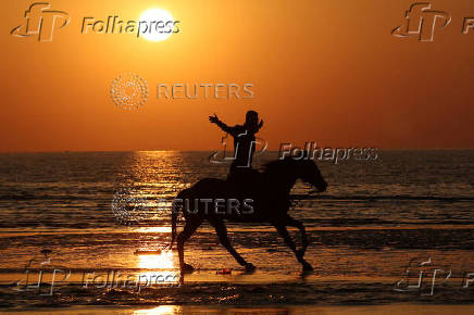 People ride horses during sunset as temperatures rise near Durres