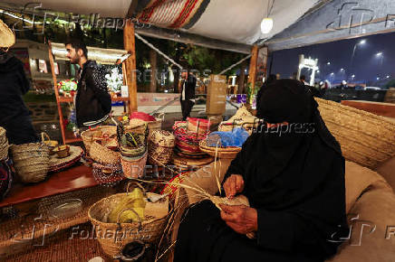 A Saudi woman weaves a basket using traditional method at a Cultural and Heritage Festival in downtown Abha, Saudi Arabia