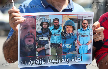 A demonstrator holds a poster during a protest in solidarity with journalists in Gaza, in Sidon