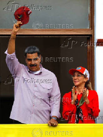 Venezuelan President Nicolas Maduro, greets supporters besides his wife Cilia Flores, during a march marking the first anniversary of his victory in the disputed July 28 presidential election, in Caracas