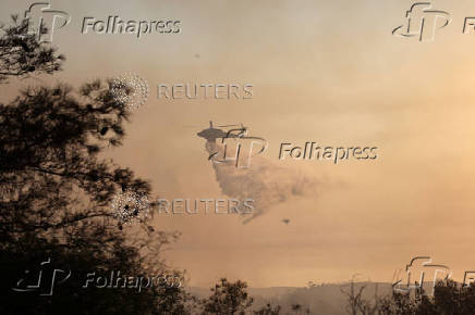 A firefighting helicopter drops water to extinguish fire at the area of Souni near Limassol,