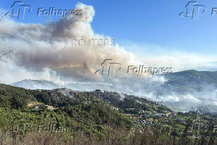 Smoke from a wildfire rises over the hills near the village of Canelas