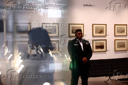 A security personnel stands guard with water colored paintings by David Roberts visble in the background, at Sotheby's