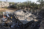 Palestinians inspect the damage at the site of an Israeli strike on a house, in Deir Al-Balah in the central Gaza Strip