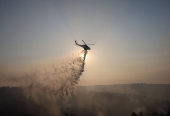 A firefighting helicopter drops water to extinguish fire at the area of Souni near Limassol,