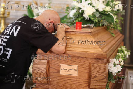 A mourner stands next to the coffin of Ziad Rahbani, during his funeral in Bikfaya