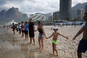 People attend a symbolic ritual named 'O Abraco' marking the World Oceans Day, at Sao Conrado beach in Rio de Janeiro