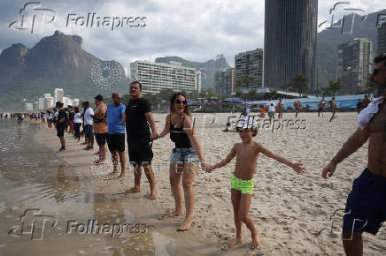 People attend a symbolic ritual named 'O Abraco' marking the World Oceans Day, at Sao Conrado beach in Rio de Janeiro