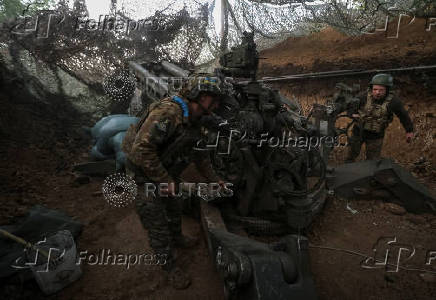 Servicemen fire a howitzer towards Russian troops at a position on front line in Donetsk region