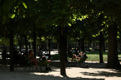 People sit on chairs in the Tuileries Garden on a warm and sunny day in Paris