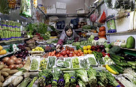 FILE PHOTO: A vendor reaches out for vegetables at her shop in a market in Beijing