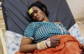 An injured woman recovers in a hospital bed following a drone strike
